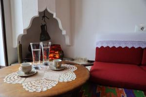 a coffee table with two glasses and a red couch at Oda e Skulptorit-UNESCO quarter in Berat