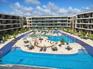 an image of a resort pool with tables and chairs at Flat em muro alto in Ipojuca