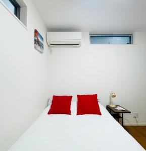 a bedroom with a white bed with two red pillows at Alo BnB 5 - Near NIPPORI, SENDAGI, YANAKA GINZA, UENO - Self check-in in Tokyo