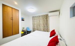 a bedroom with a white bed with red pillows at Alo BnB 5 - Near NIPPORI, SENDAGI, YANAKA GINZA, UENO - Self check-in in Tokyo