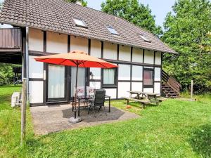 une table avec un parasol devant une maison dans l'établissement Apartment Am Sternberg 230 by Interhome, à Frankenau