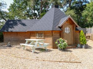 a wooden cabin with a picnic table in front of it at Enchanted Cottage in Snettisham
