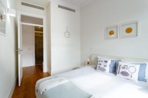 a white bedroom with a large bed with blue pillows at Restauradores Prime Loft in Lisbon