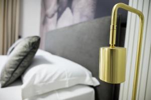 a gold lamp next to a bed with a pillow at Soulmade Residence in Cosenza +89 photos