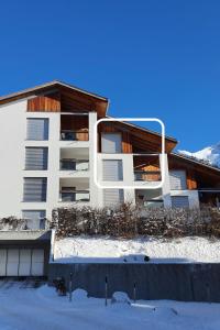 a white apartment building in the snow at Apartment Ferienwohnung Kinsella by Interhome in Lenzerheide