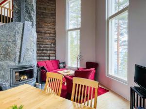 ein Wohnzimmer mit Tisch und Kamin in der Unterkunft Holiday Home Huvila lomaonni by Interhome in Kolinkylä