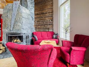 ein Wohnzimmer mit roten Stühlen und einem Kamin in der Unterkunft Holiday Home Huvila lomaonni by Interhome in Kolinkylä + 28 Fotos
