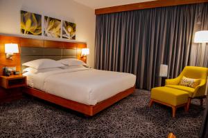 a bedroom with a large bed and a yellow chair at Hilton Garden Inn Nairobi Airport in Nairobi