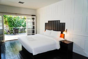 a bedroom with a large white bed and a patio at Luna Hut Resort in Hua Hin