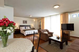 Habitación de hotel con cama y sala de estar. en Suites Metropoli, en Quito