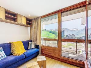 a living room with a blue couch and a large window at Apartment Chavière 716 by Interhome in Les Menuires +33 photos