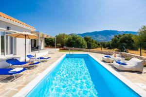 una piscina con sedie e ombrelloni accanto a una casa di Villa Tania Dio a Karavádhos