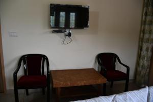 a room with two chairs and a table and a tv at Negi Hotel in Mukteshwar