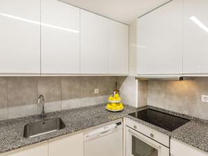 Una cocina con gabinetes blancos y un fregadero. en Apartment Guardamar by Interhome, en Miami Platja