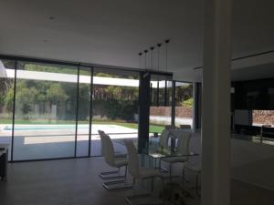 a dining room with a glass table and white chairs at Casa de lujo en Gavá mar in Gavà