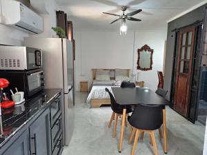 a kitchen with a table and a bedroom with a bed at R Garden Studio 2 moderne pour couple dans un cadre relaxant et confortable in Port Louis