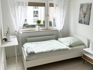 a white bedroom with a bed and a window at Work & Stay Troisdorf in Troisdorf