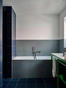 a blue tiled bathroom with a tub and a sink at LUIS Boutique Hotel in Aalen +6 photos