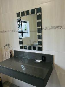 Un baño con encimera negra y espejo. en Heavenly Towers, en Mbazwana