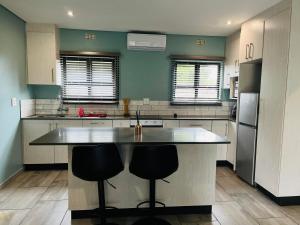 a kitchen with a large island with two bar stools at Heavenly Towers in Mbazwana +8 photos