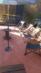 Un grupo de sillas y una sombrilla en un patio. en La Obra Vintage, en Ciudad Evita