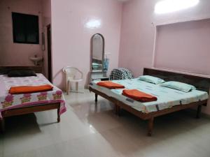 a bedroom with two beds and a mirror at Shivam Residency in Ellora
