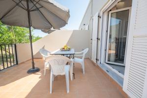 a table and chairs on a balcony with an umbrella at Stone and Sea Kos Oasis in Kos Town