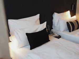 two beds with white sheets and a black pillow at Bold Hotel München Giesing in Munich