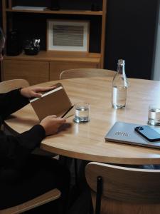 a person sitting at a table with a book and a bottle at Bold Hotel München Giesing in Munich