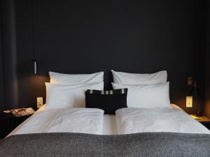 a bedroom with a bed with white pillows at Bold Hotel München Giesing in Munich
