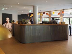 two people sitting at a bar in a restaurant at Bold Hotel München Giesing in Munich