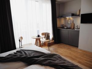 a bedroom with a bed and a table and a kitchen at Bold Hotel München Giesing in Munich