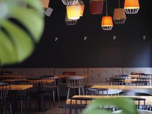 an empty restaurant with tables and chairs and lights at Bold Hotel München Giesing in Munich