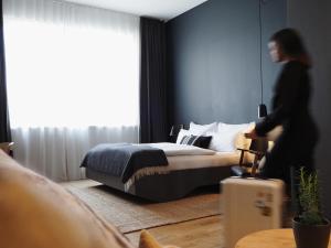 a woman walking through a bedroom with a bed at Bold Hotel München Giesing in Munich