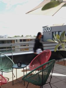 a woman walking past chairs and tables on a roof at Bold Hotel München Giesing in Munich