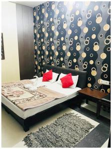 a bedroom with a bed with red pillows and a wall at Amritsar Hotel R-A-M-N-E-E-K Near Bus Stand - Spacious Rooms With Free Wi-fi - Restaurant# Parking & Excellent Customer Service - Best Location In Amritsar in Amritsar