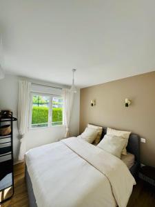una camera da letto con un grande letto bianco con una finestra di La maison de Lili a Mercin-et-Vaux