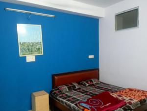 a bedroom with a blue wall and a bed at RL Residency in Jāmb