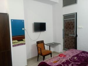 a bedroom with a bed and a chair and a tv at RL Residency in Jāmb