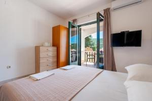 a bedroom with a bed and a tv and a balcony at Villa Piccolotti in Neum