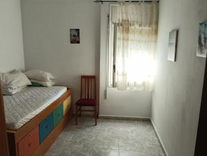 a bedroom with a bed and a chair and a window at Apartamento en Blanes in Blanes