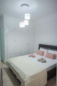 - une chambre blanche avec un grand lit et des oreillers roses dans l'établissement Sunset Waves, à Menídion