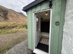 ein grün-weißer Schuppen mit offener Tür in der Unterkunft Altchourunn Cottage in Acharra
