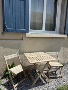 stół piknikowy i dwa krzesła przed budynkiem w obiekcie Le Côté Cour w mieście Barcelonnette
