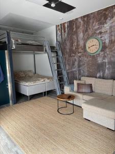 a room with bunk beds and a couch and a clock at Loft style big studio for 2-4 in Pikku Huopalahti in Helsinki
