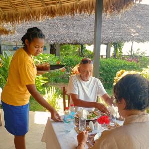 a man and woman sitting at a table eating food at WINGS HOTELS in Nosy Be