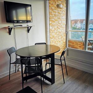 a dining room with a table and chairs and a tv at Les pieds dans l'eau - loggia exposée plein sud in Courseulles-sur-Mer