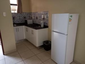 cocina con nevera blanca y suelo de baldosa en PALACE LODGE PINETOWN, en Pinetown