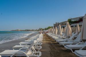 eine Reihe von Liegestühlen und Sonnenschirmen am Strand in der Unterkunft Tropic Beach Resort Hotel in Side