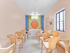 アジメールにあるOYO 85212 Hotel Vaibhavの椅子とテーブル(壁に絵画付)が備わるお部屋